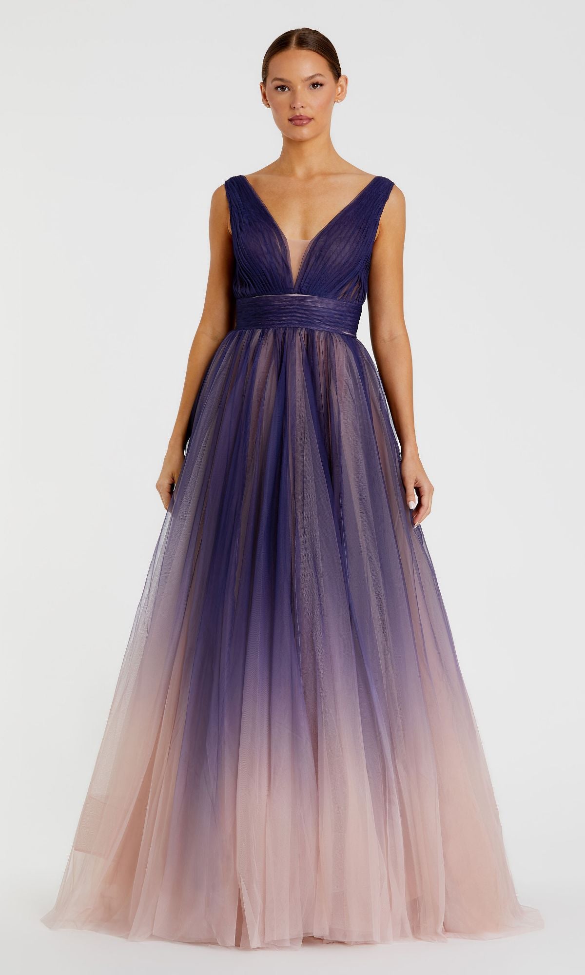 A woman wears the Indigo Ombre Prom Ball Gown: Mac Duggal 20221, featuring an indigo A-line silhouette, deep V-neck, and a gradient tulle skirt that shifts from dark purple to light pink.